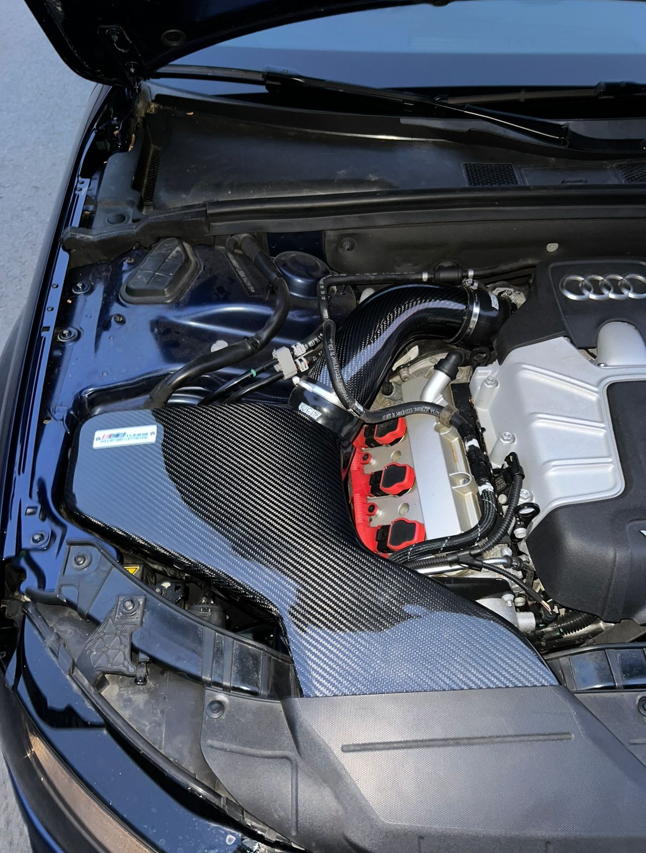 A close up of a car engine with the hood open
