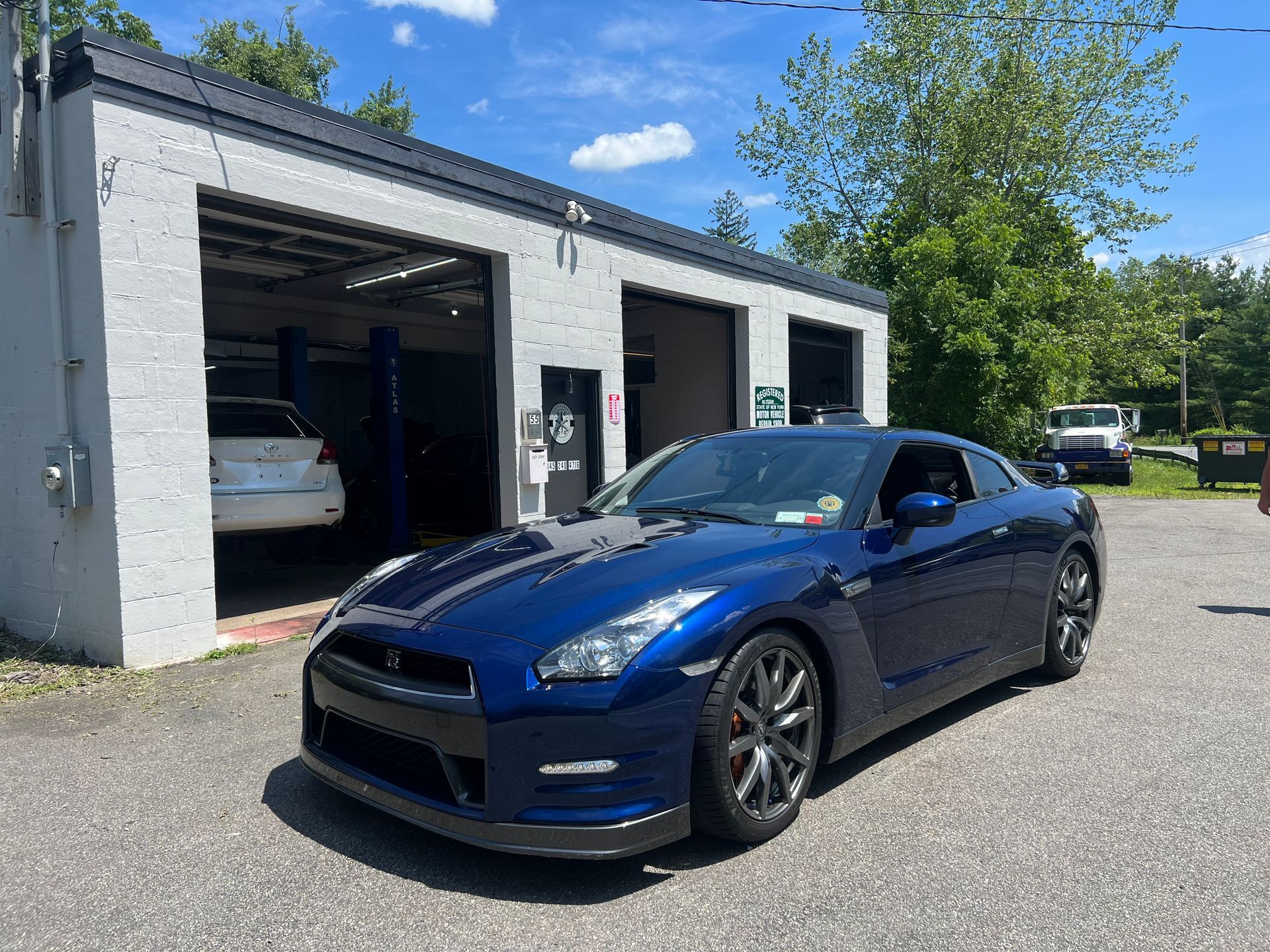 A blue sports car is parked in front of a garage.