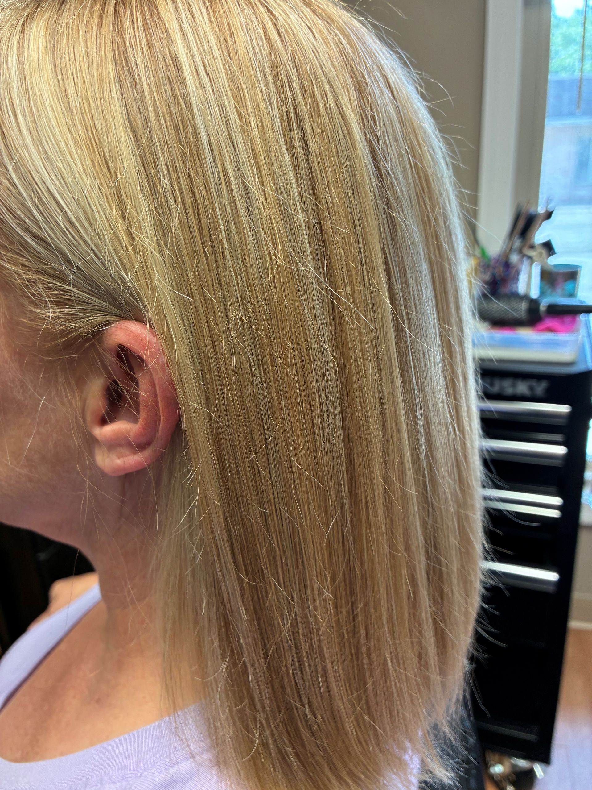 Blonde layered bob haircut shown from the side in a salon setting