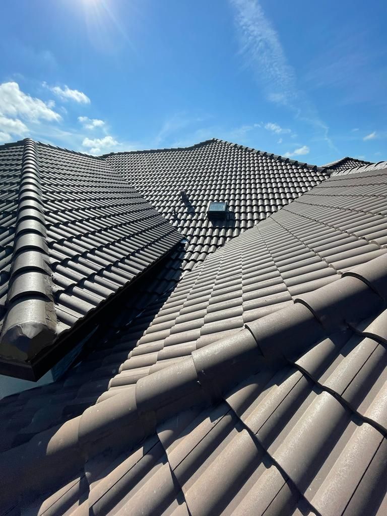 Gray tiled roof with skylight under a clear blue sky