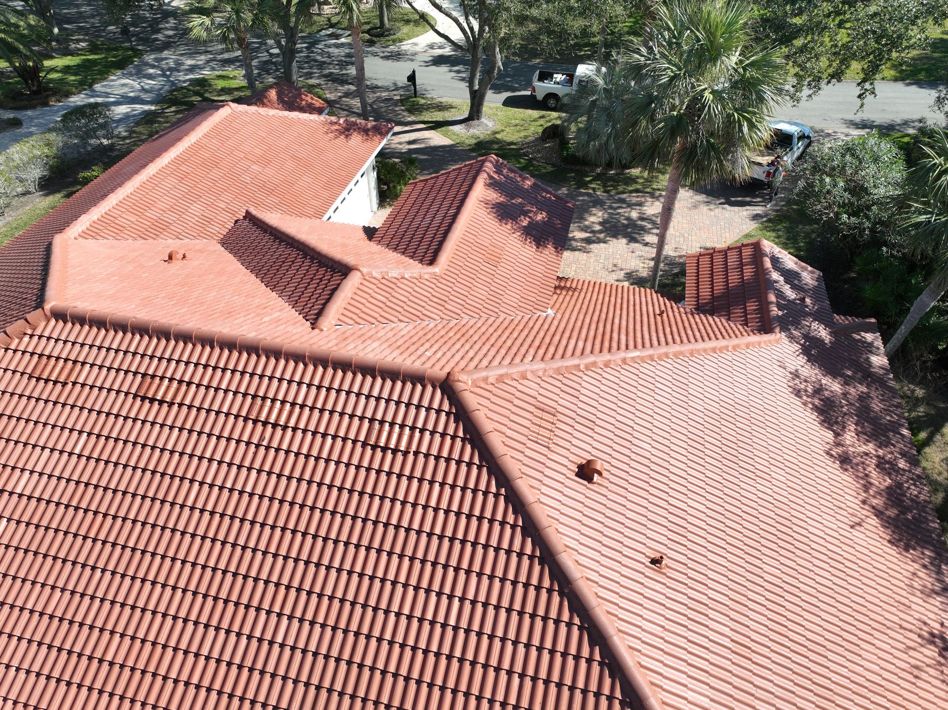Aerial view of a house with red tile roof surrounded by trees and a driveway