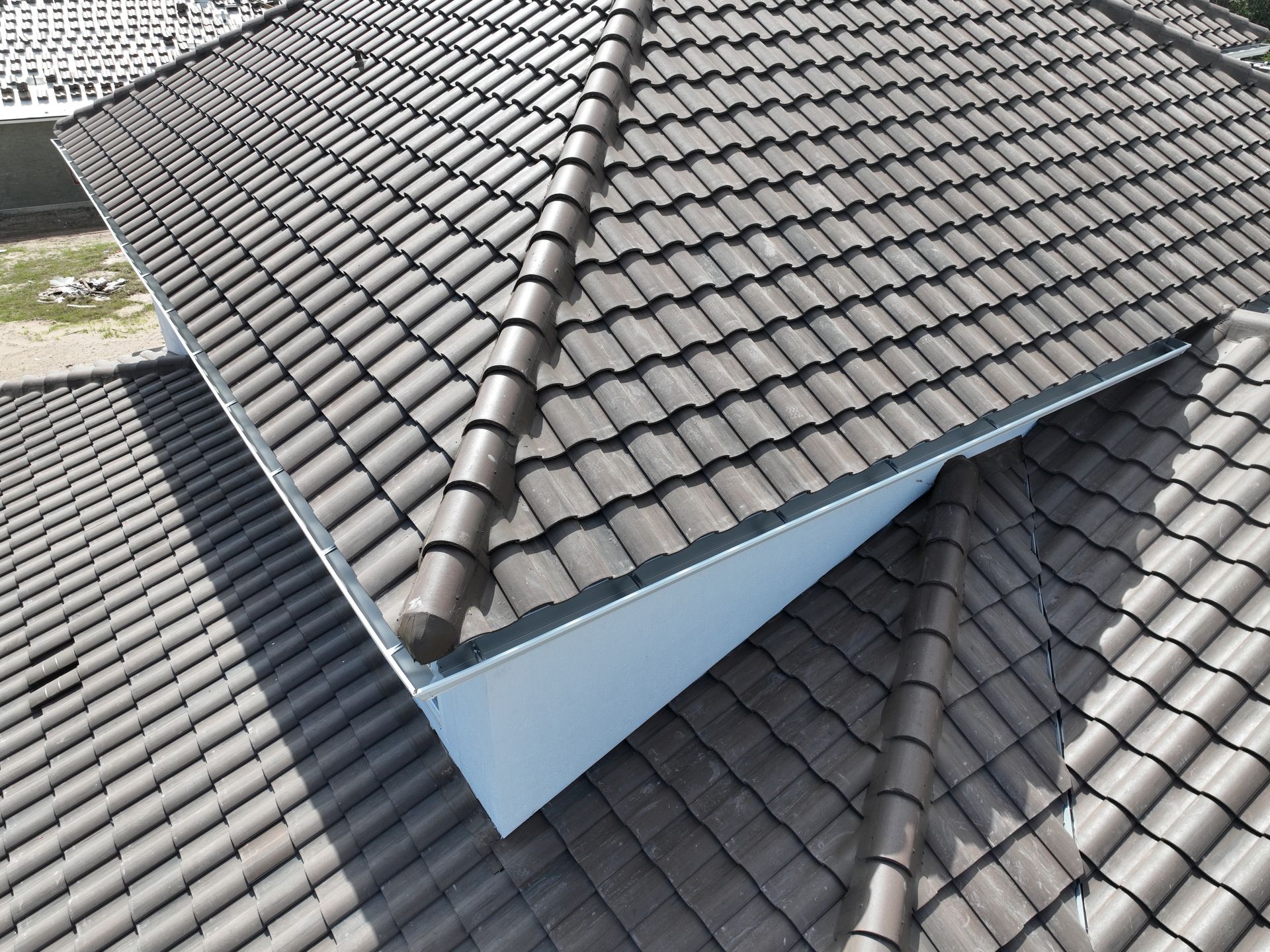 Roof with gray tiles and a blue dormer-like structure intersecting two sloped sections