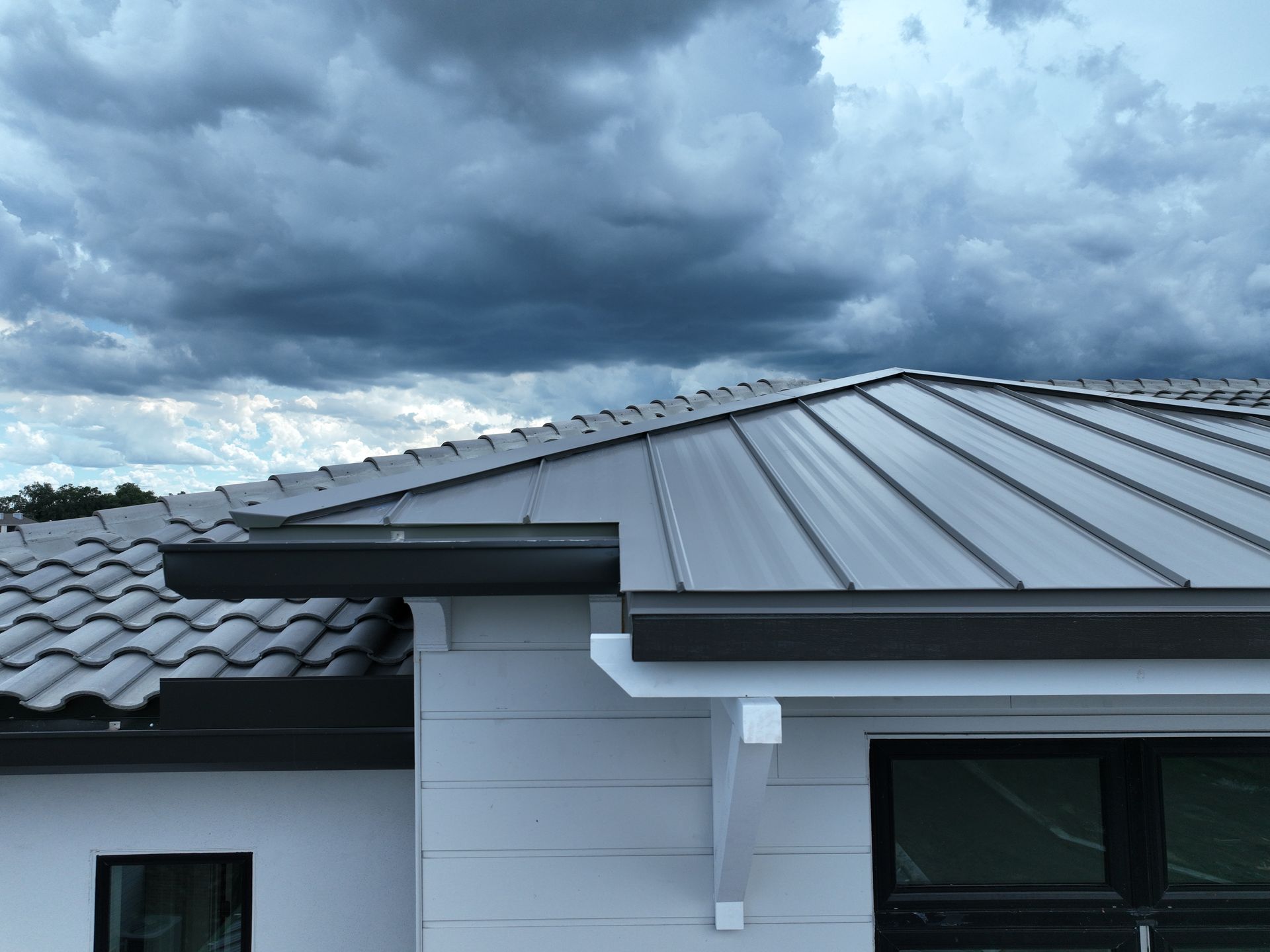 Modern house roof with gray metal panels under a cloudy sky