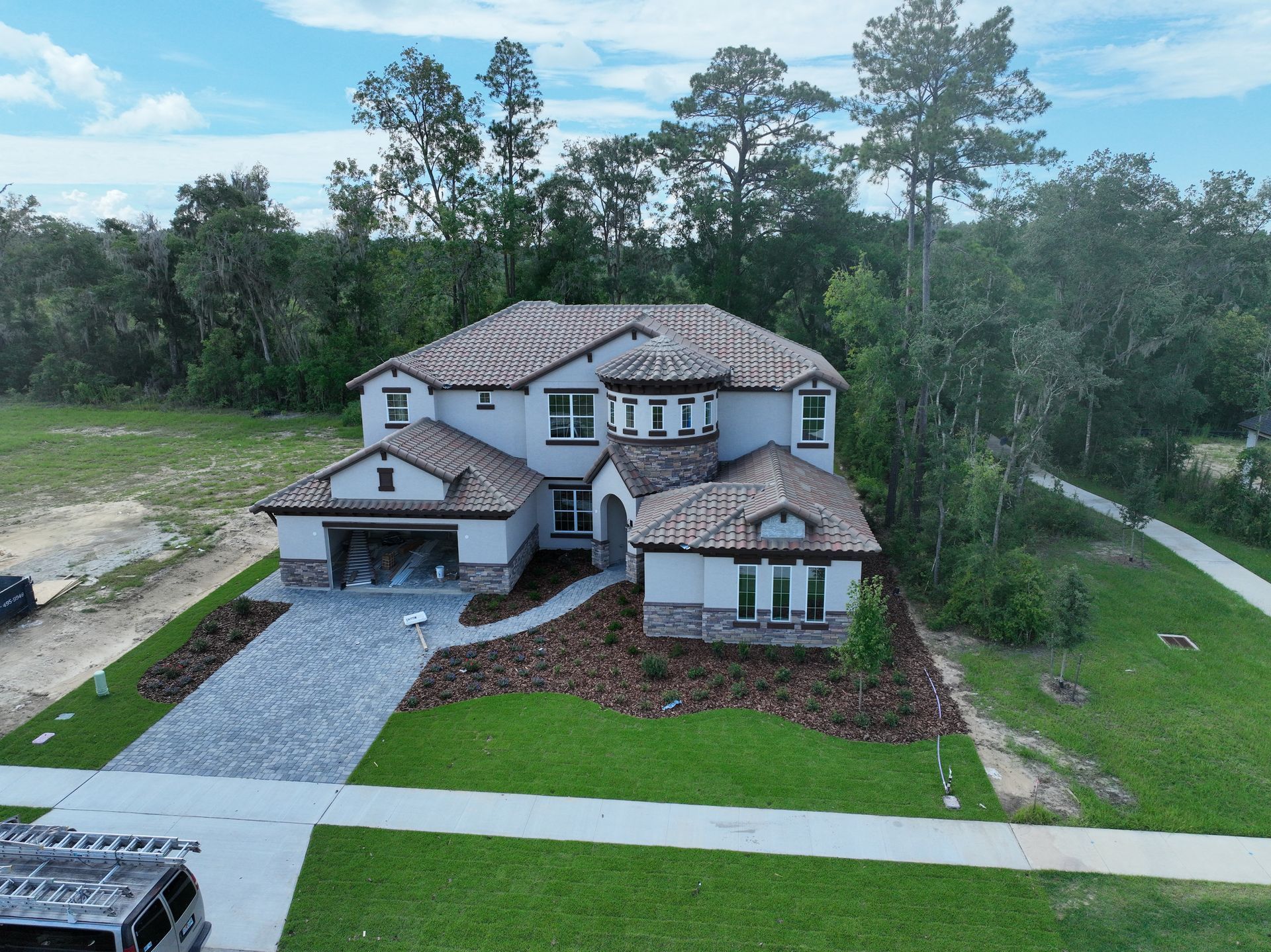 Aerial view of a large gray two-story suburban house with a tile roof and landscaped yard.
