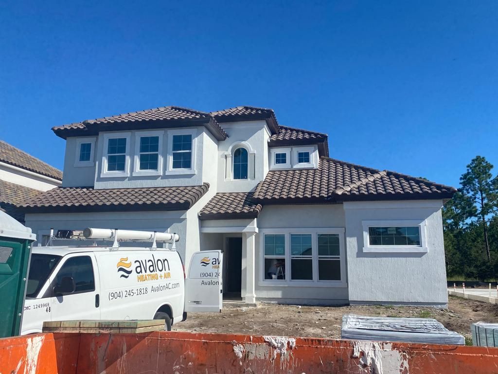 New white two-story house under construction with white van and building materials in front