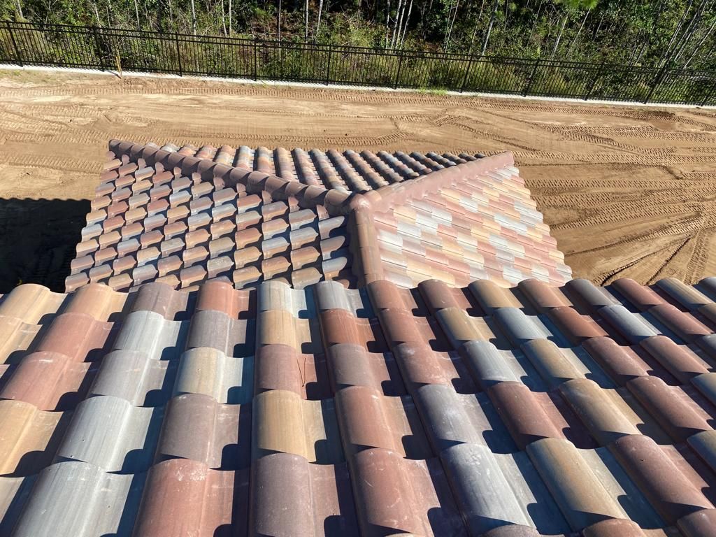 Roofing tiles on a roof under construction with a dirt yard in the background