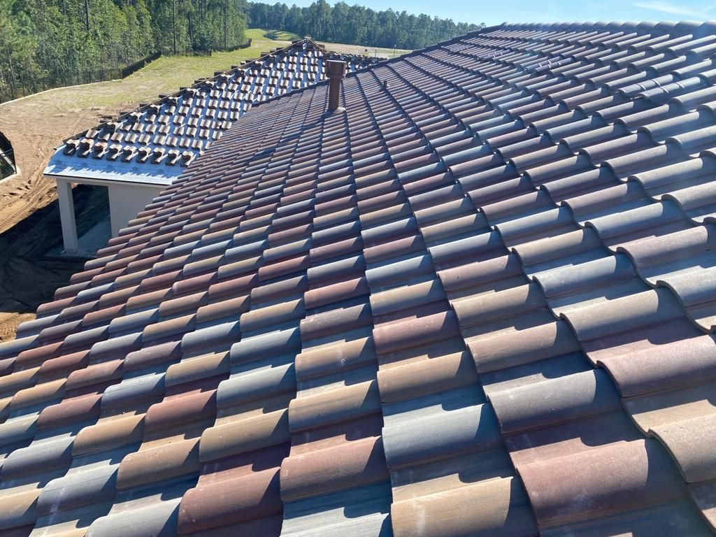 Roof covered with terracotta tiles under a clear sky, viewed from above with trees in the background