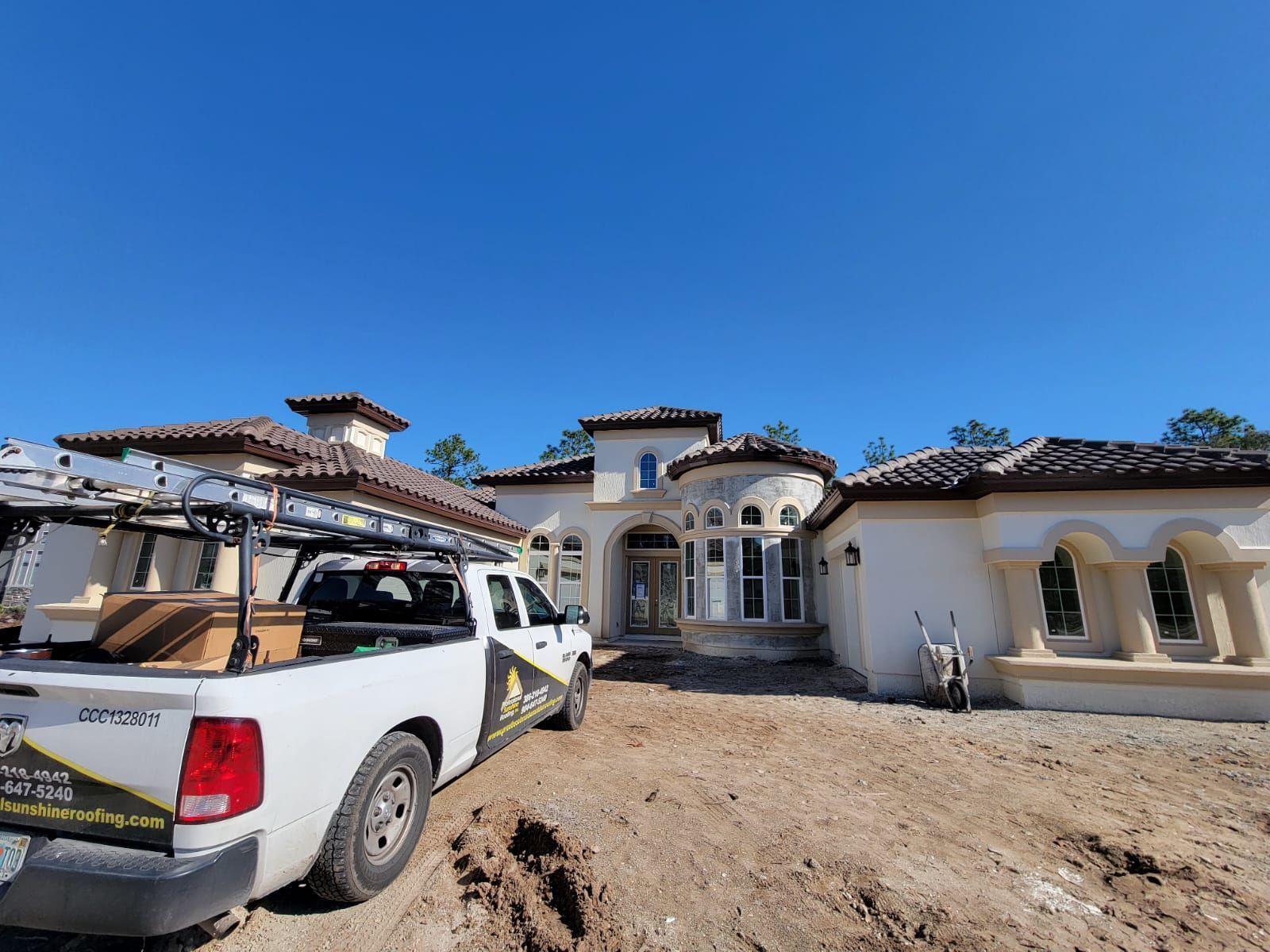White pickup truck in front of a large Spanish-style house under a clear blue sky