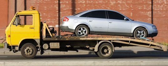 A tow truck is carrying a car on the back of it.