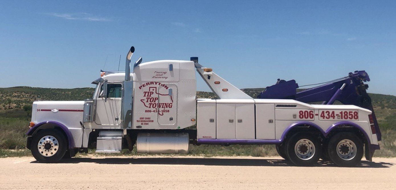 A white and purple tow truck is parked on the side of the road.