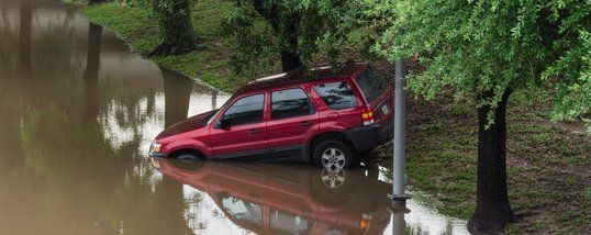 A red SUV is stuck in a flooded area.