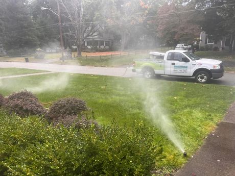 A truck is spraying water on a lush green lawn.