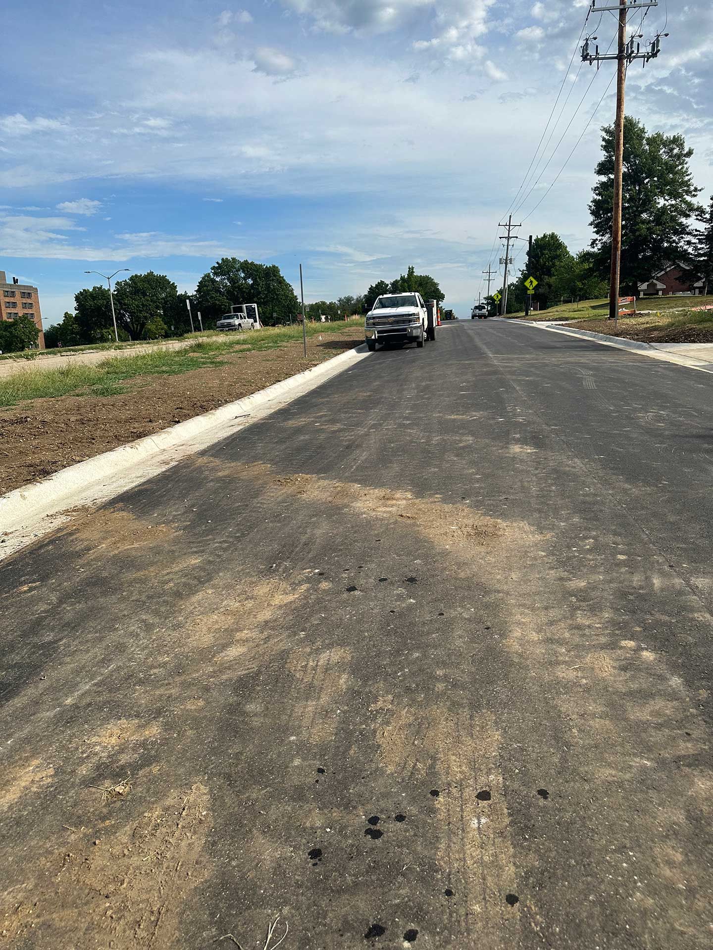 a car is driving down a concrete road next to a field