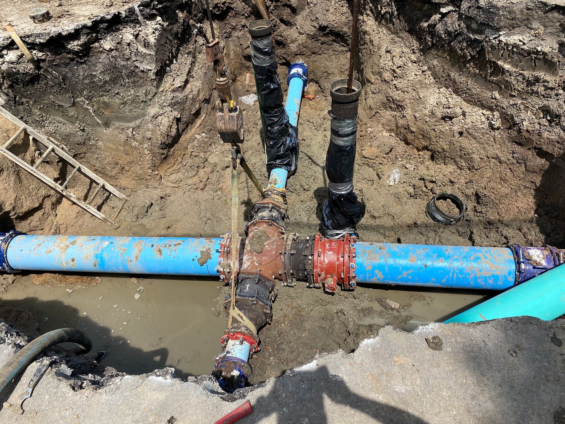 a blue pipe is sitting in the dirt next to a ladder