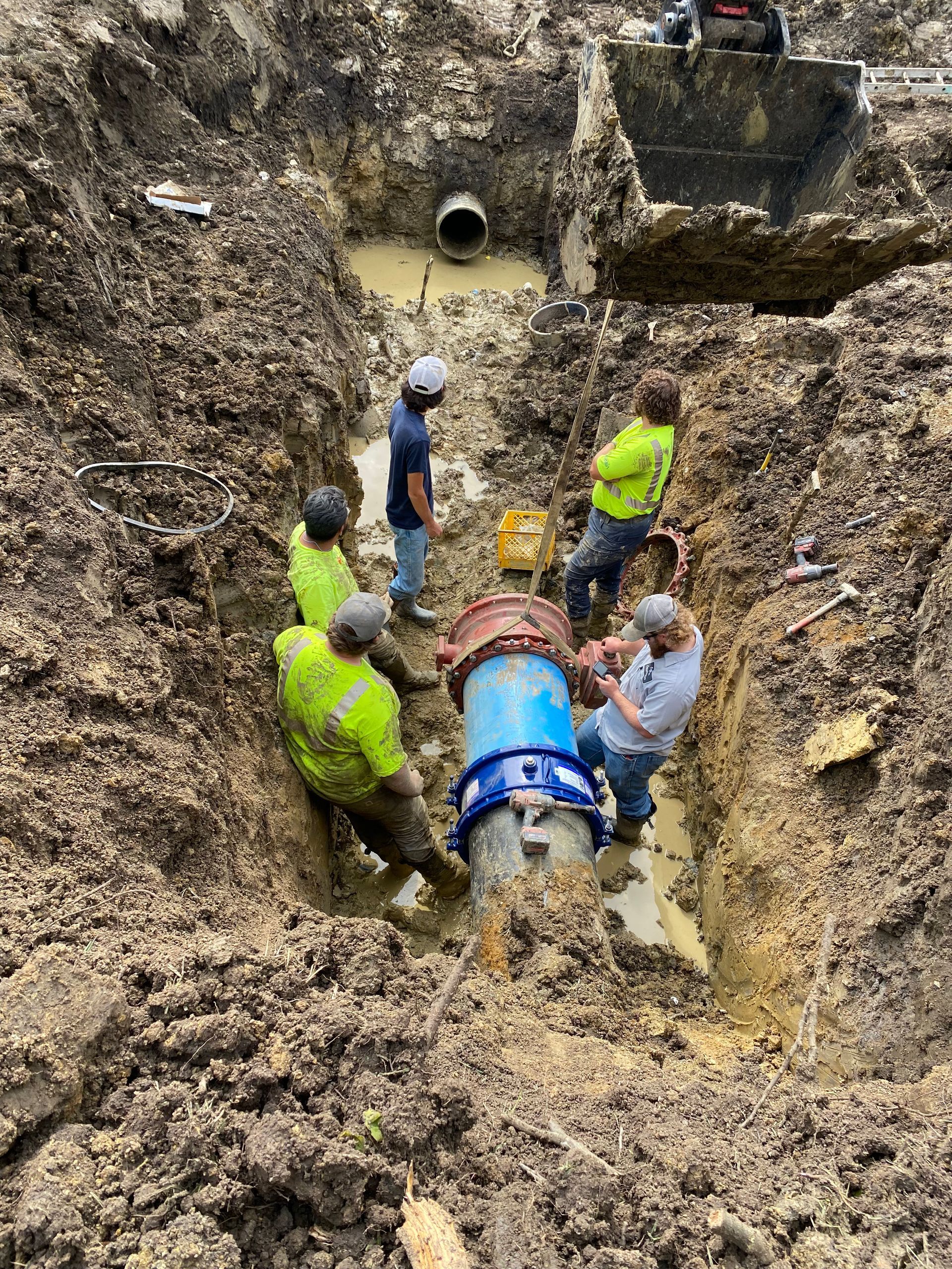 a group of men are working on a pipe in the dirt