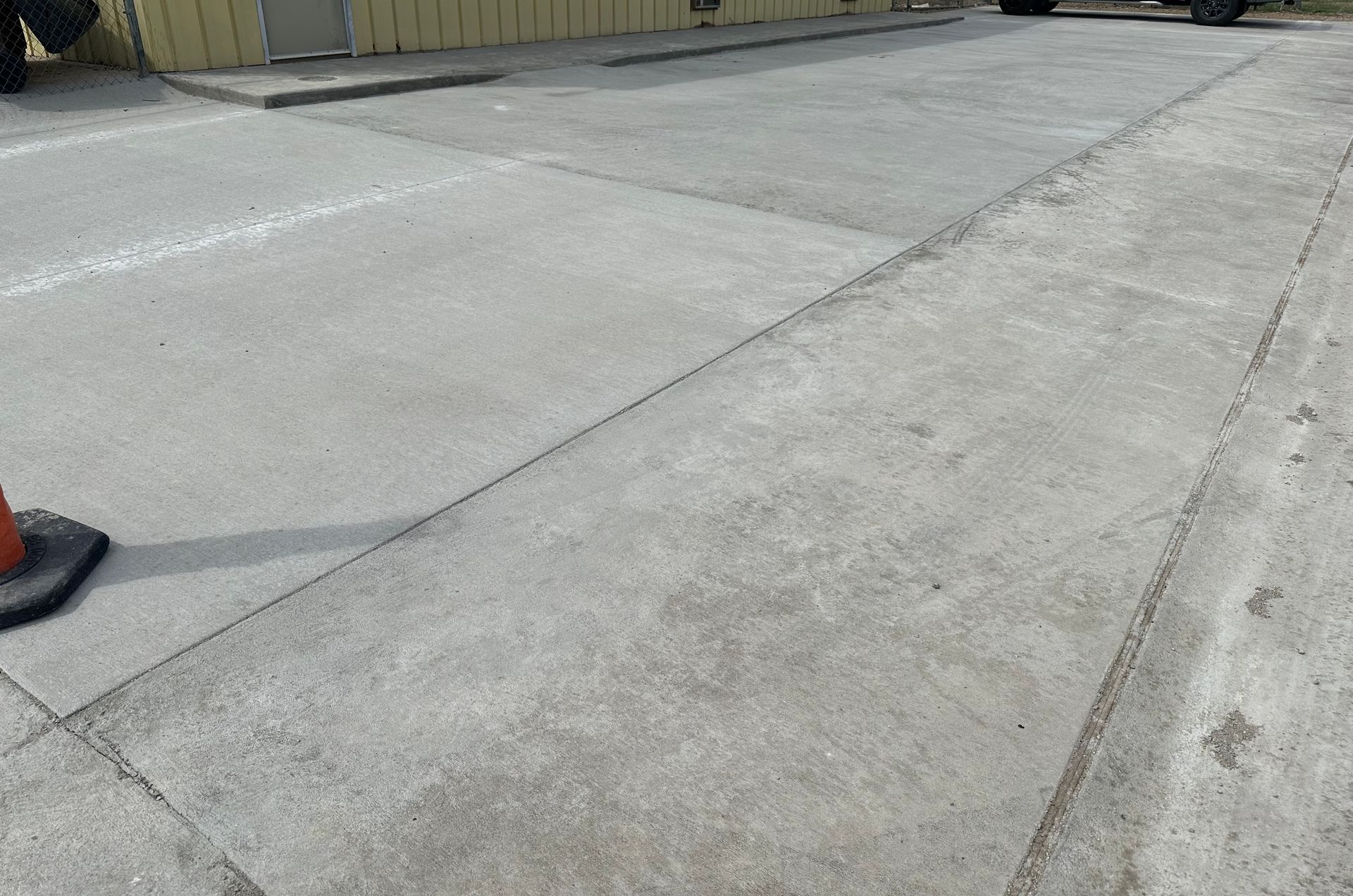 a concrete driveway with a traffic cone on the side of it