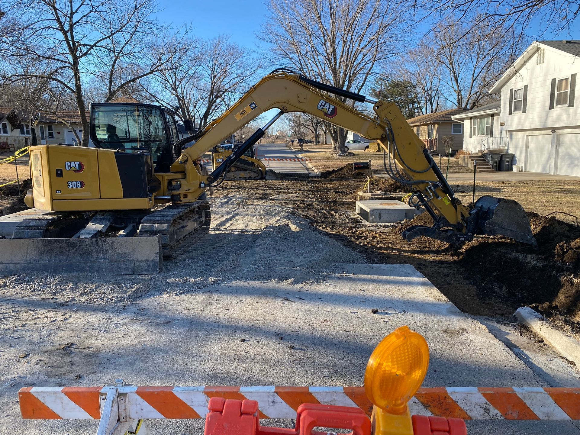 a yellow excavator is digging a hole in the middle of a street