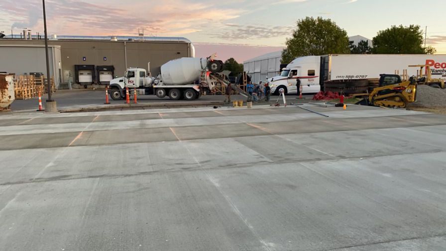 a concrete mixer truck is pouring concrete into a parking lot