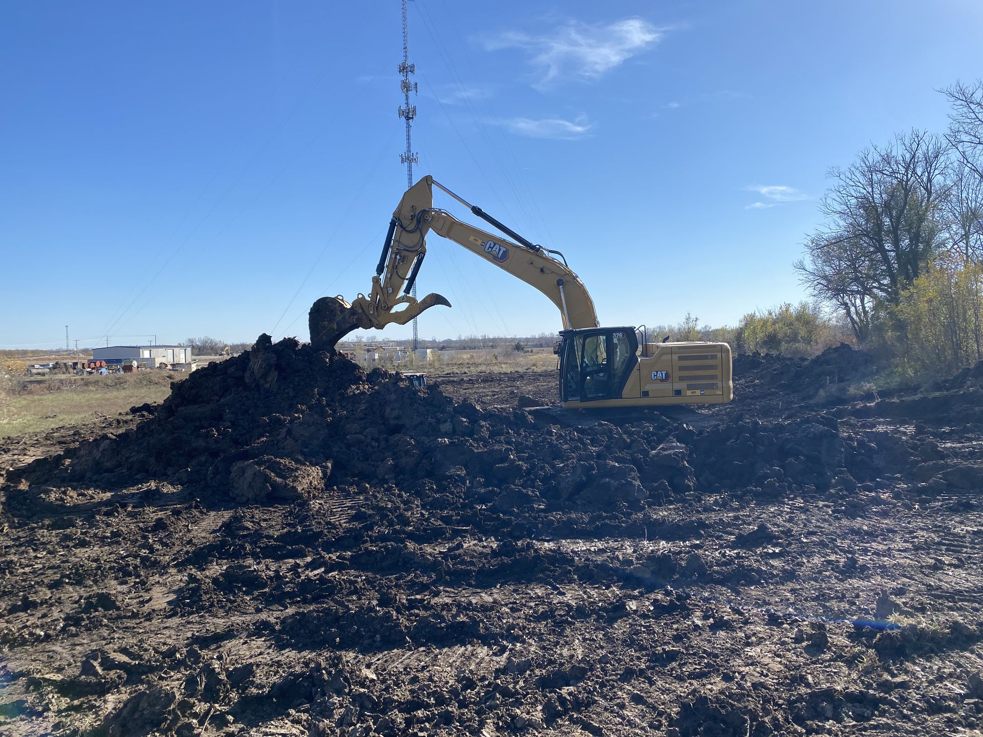 a yellow excavator is digging a pile of dirt in a field