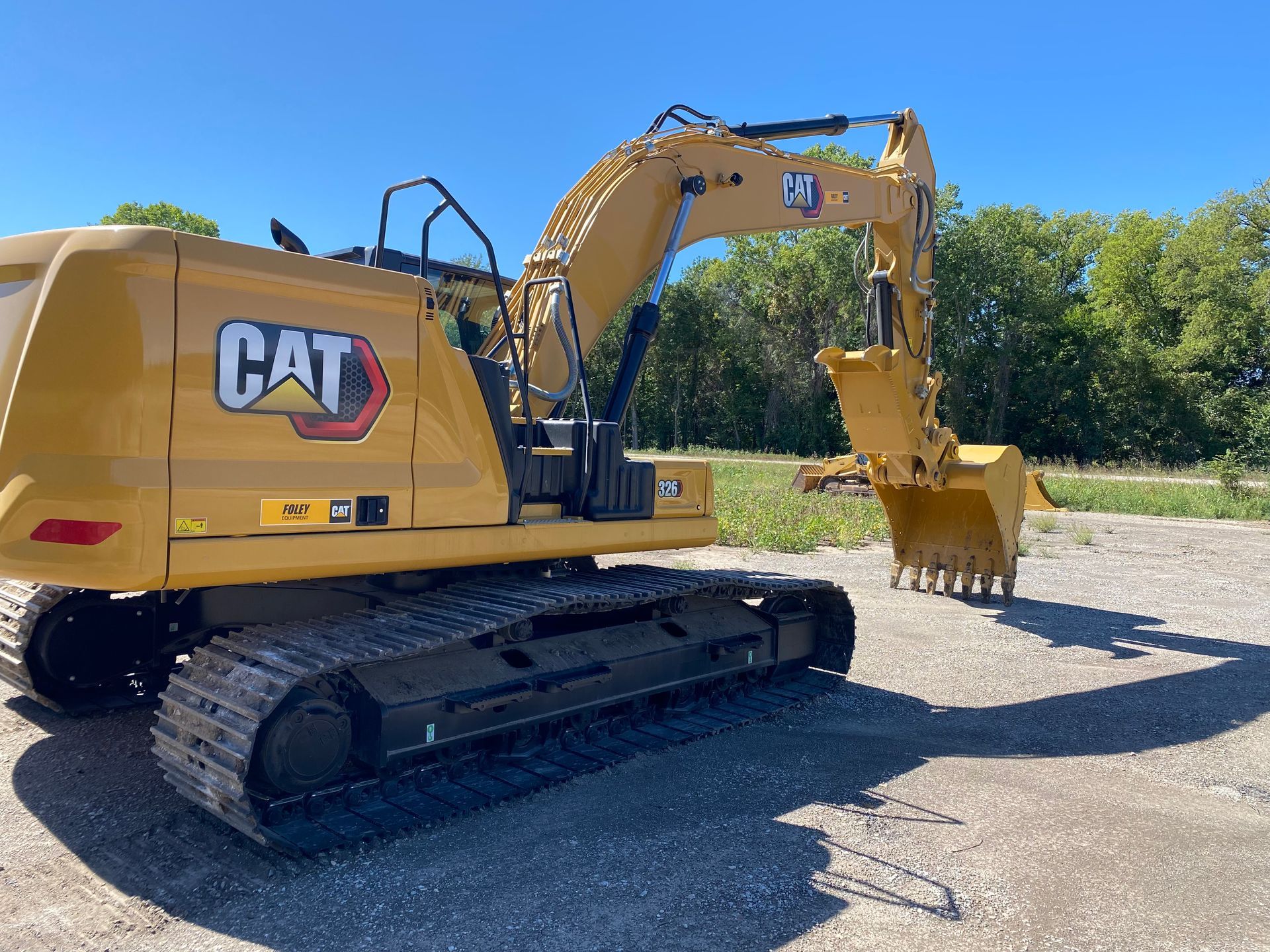 a yellow cat excavator is parked in a gravel lot