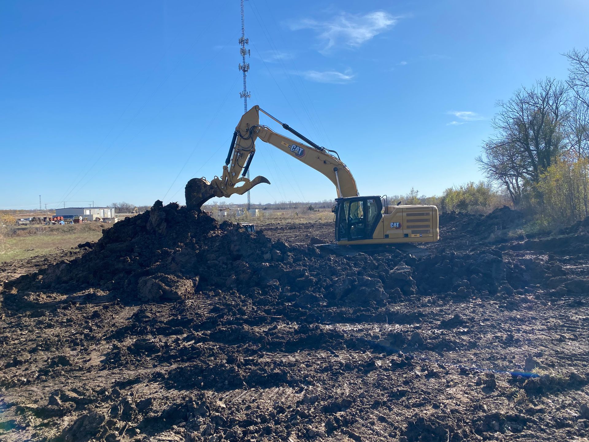 a large yellow excavator is digging a pile of dirt in a field