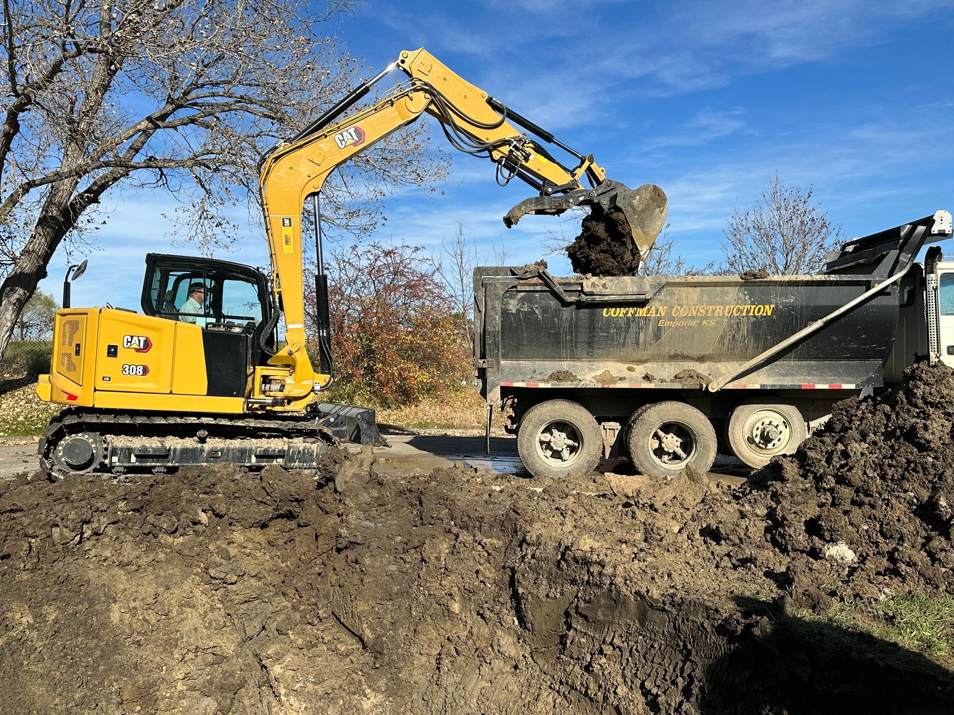 a yellow excavator is loading dirt into a dump truck