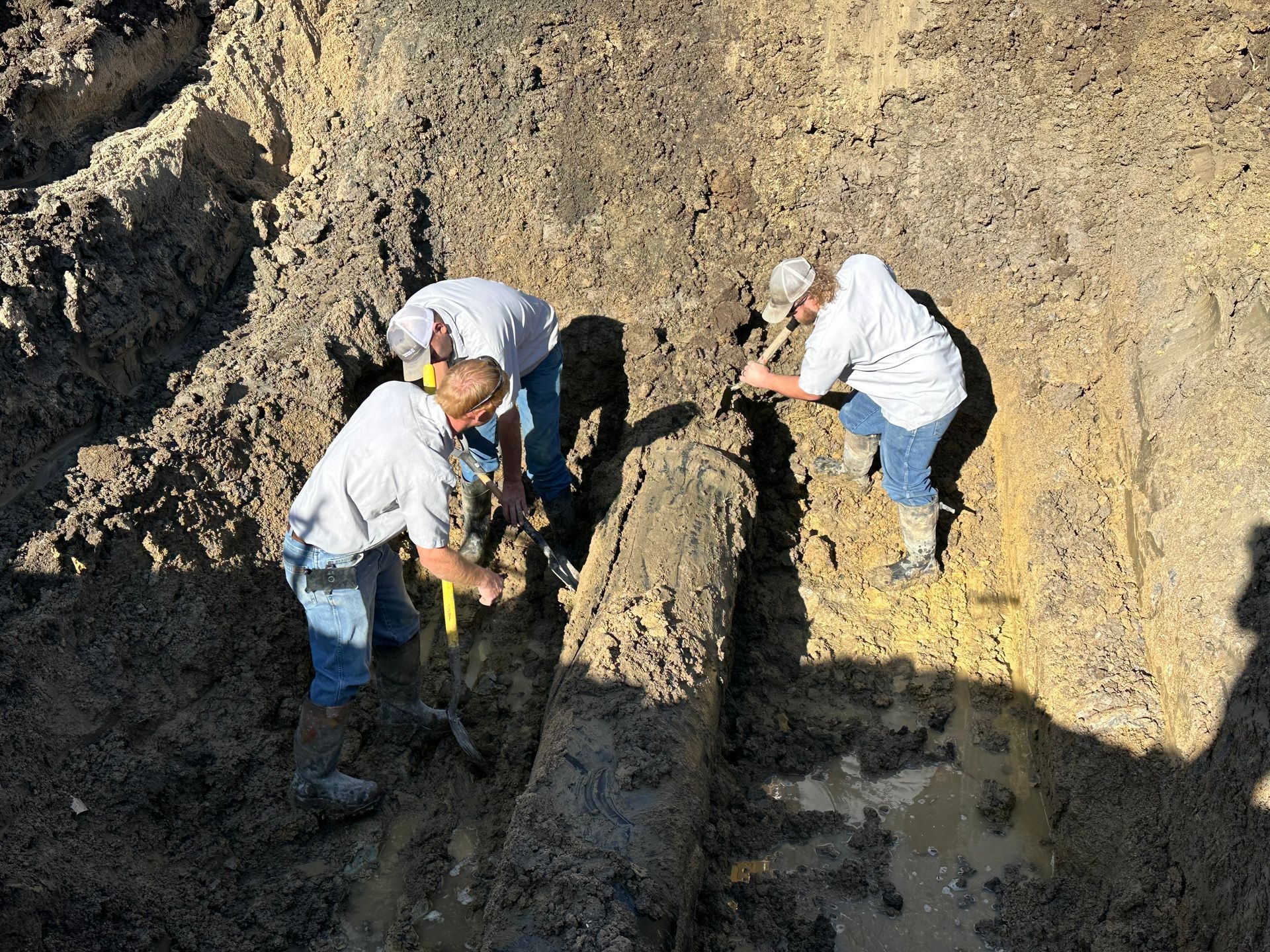 two men are working on a pipe in the dirt