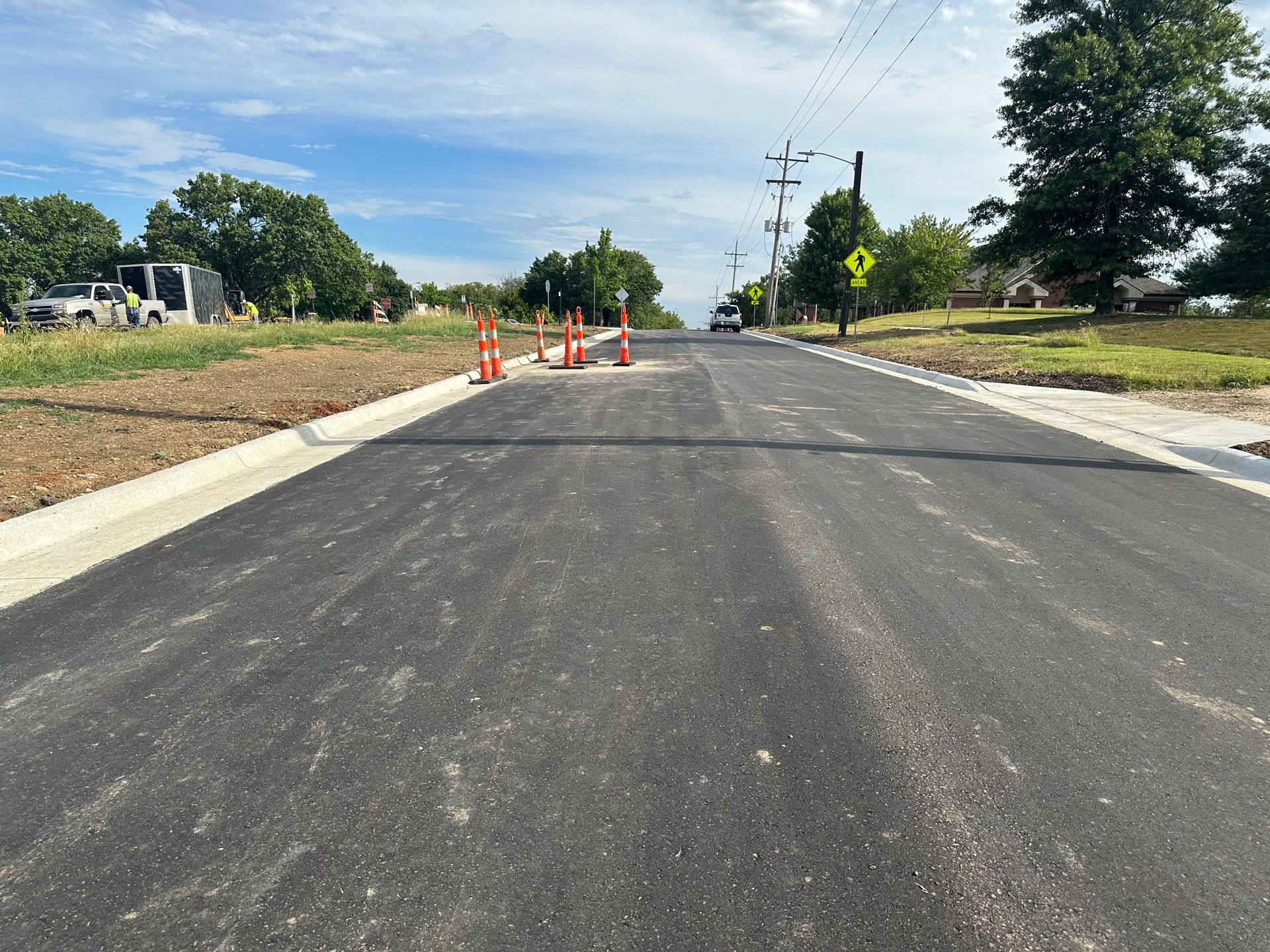a newly paved road with orange cones on the side of it