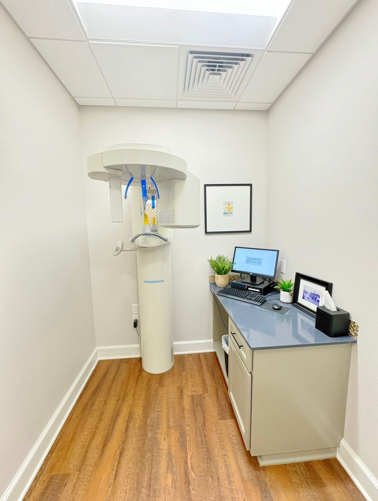 A dental office with a x-ray machine and a desk.
