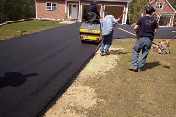 A group of men are working on a driveway in front of a house