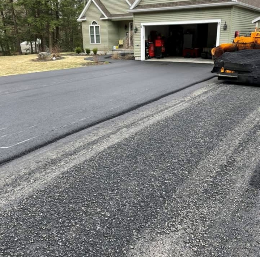 A driveway is being paved in front of a house