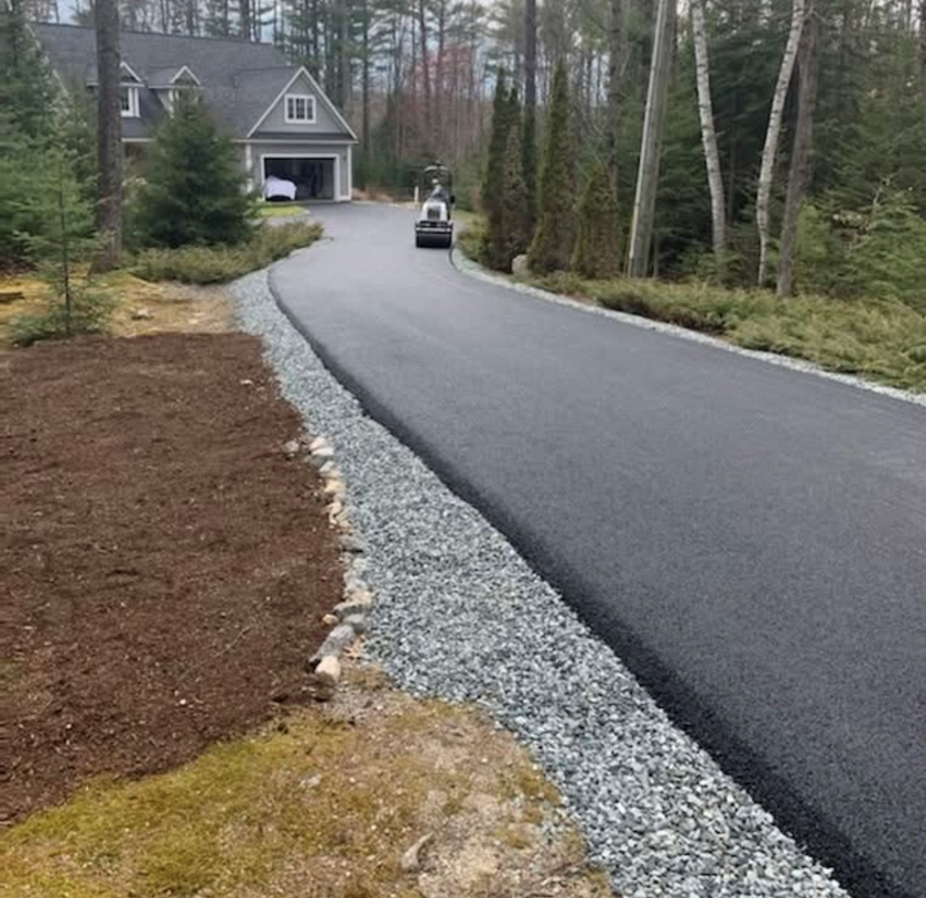 A car is driving down a road next to a house