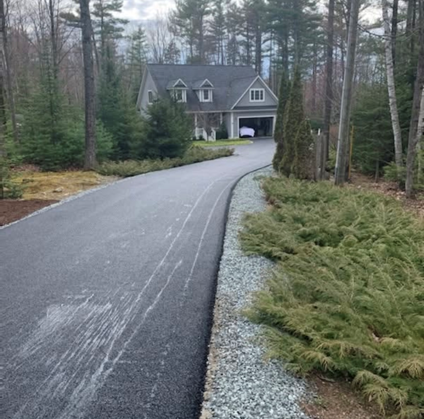 A driveway leading to a house in the woods