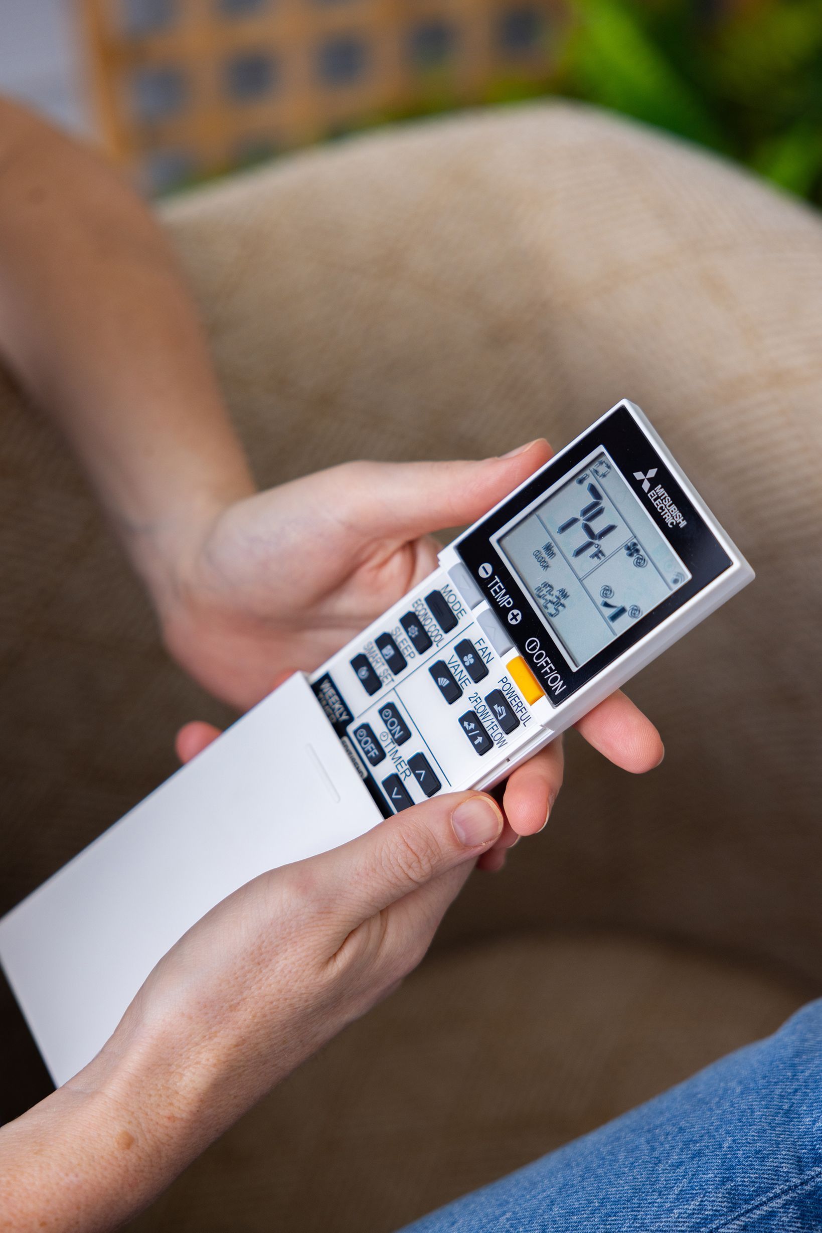 Two technicians in uniform inspect and repair an outdoor air conditioning unit installed against a residential wall.