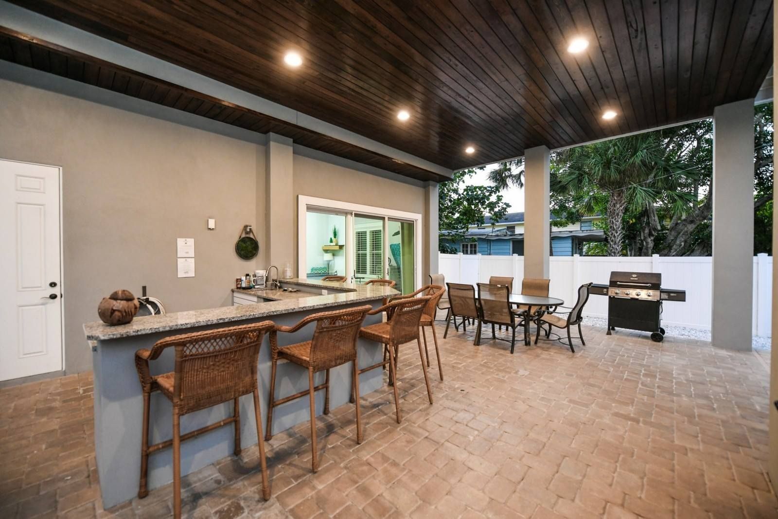 A patio with a bar, chairs, tables and a grill.