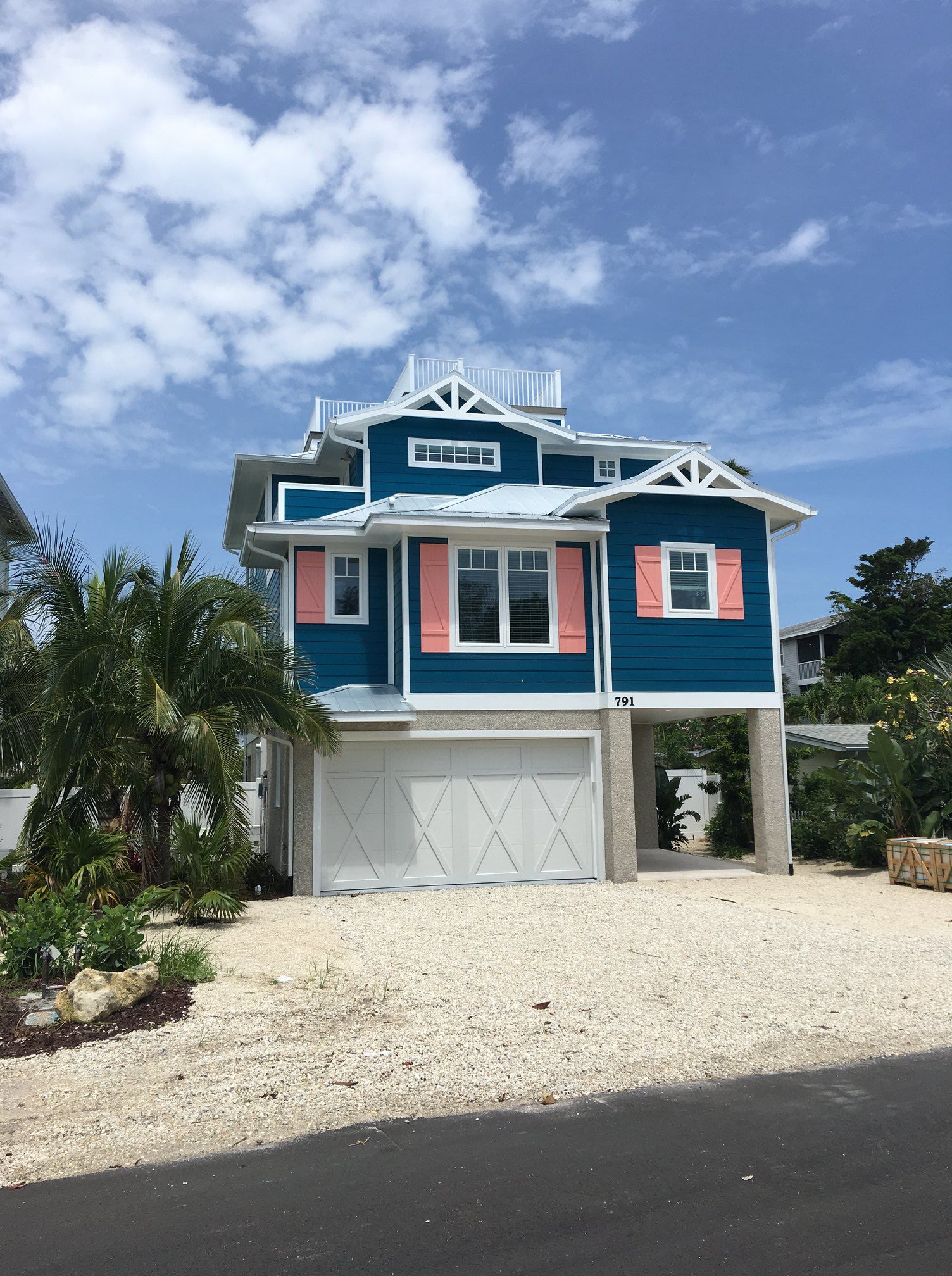 A blue and white house with pink shutters on the windows