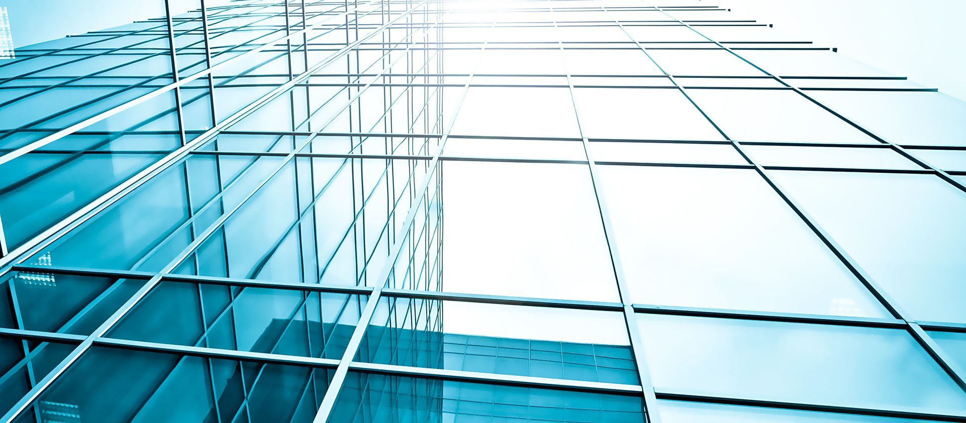 Blue glass office building facade with reflections and geometric grid lines