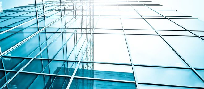 Blue glass office building facade with reflections and geometric grid lines