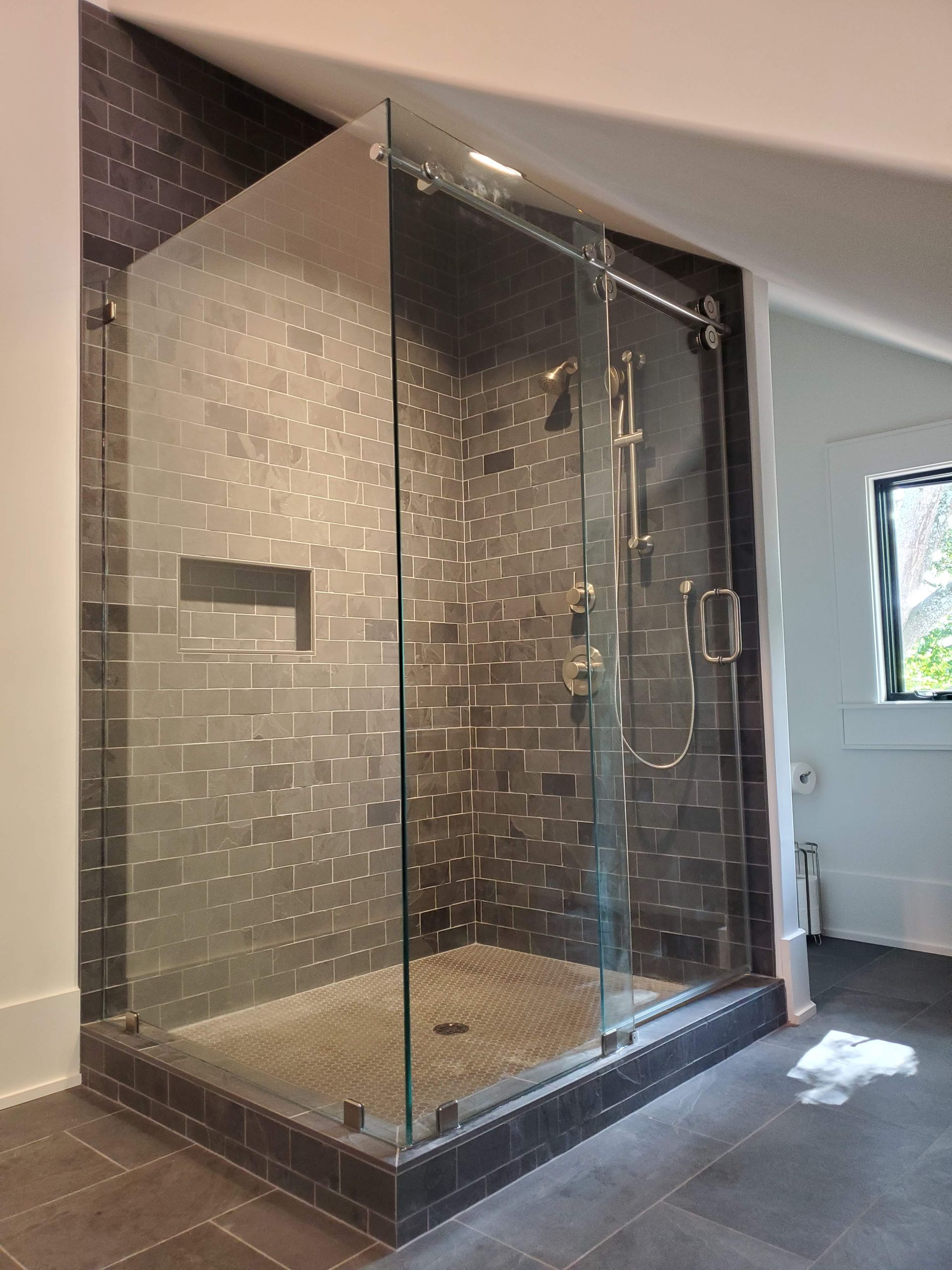Glass-enclosed shower with mosaic tile walls and a built-in bench in a modern bathroom