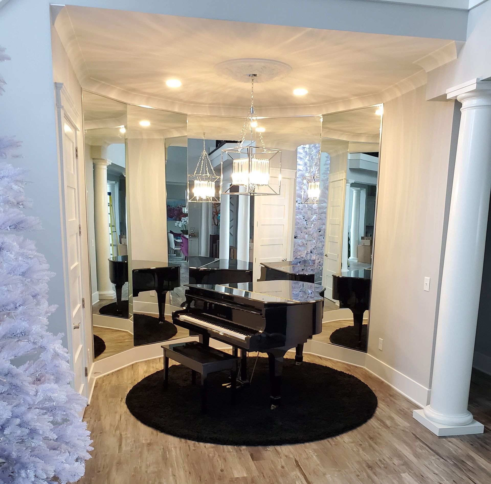 Elegant dining room with a black grand piano, mirrored walls, crystal chandelier, and round black rug