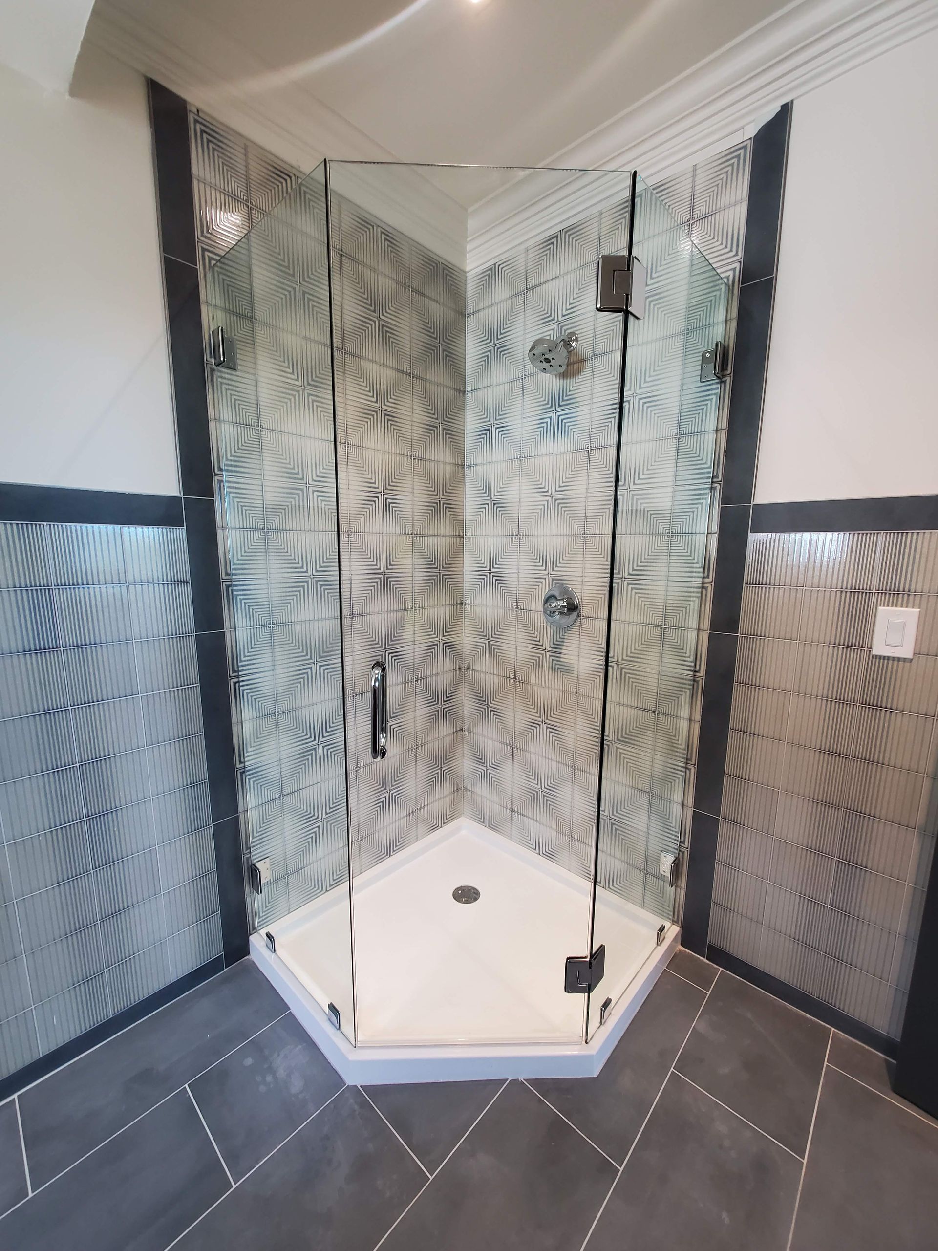 Glass shower stall with patterned walls and tiled floor in a bathroom
