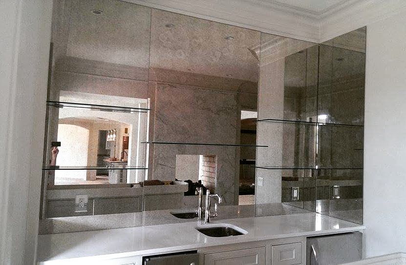 Modern bathroom with large mirrored wall, double sink vanity, and polished marble surfaces