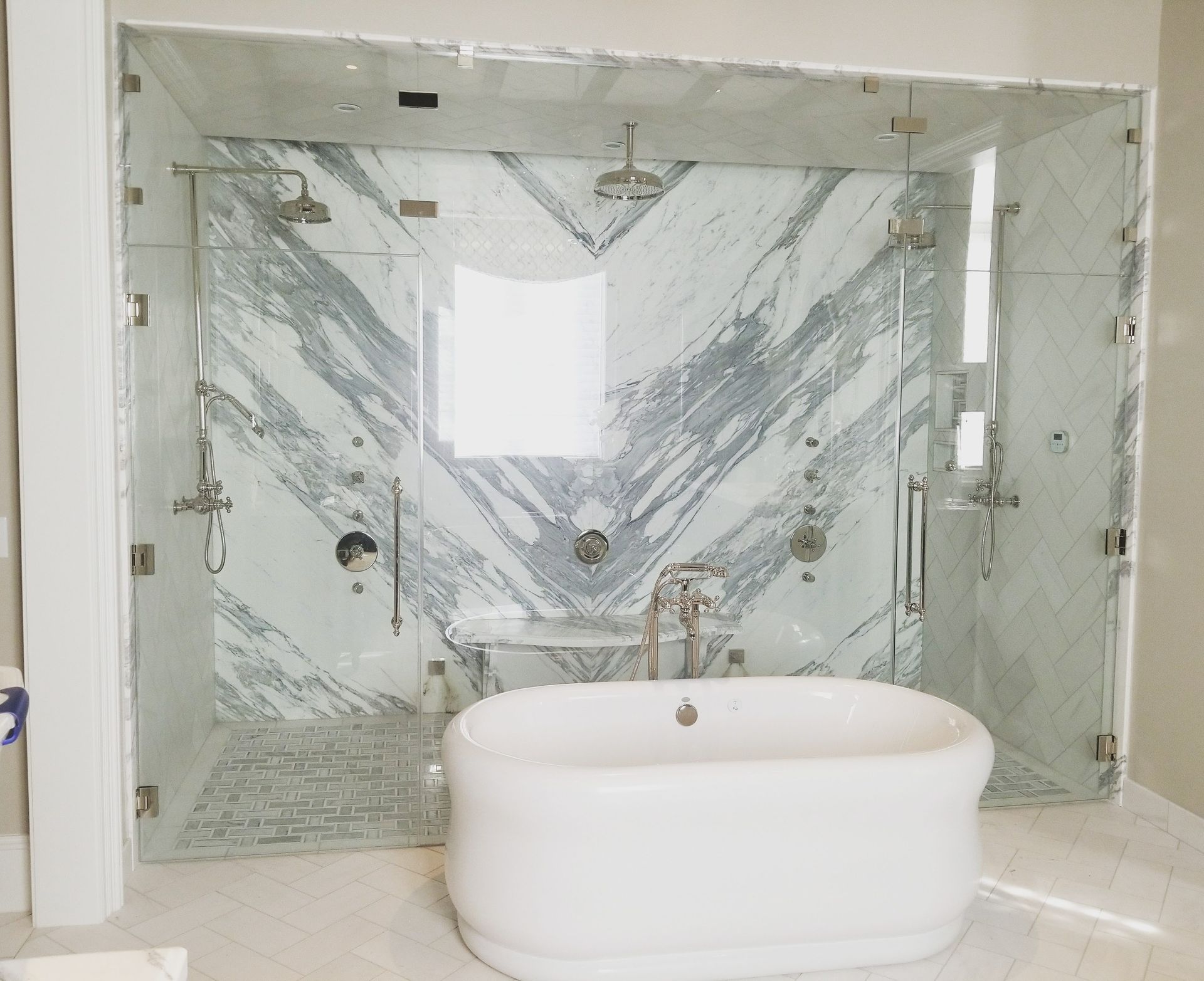 Modern marble bathroom with glass-enclosed shower and freestanding white tub