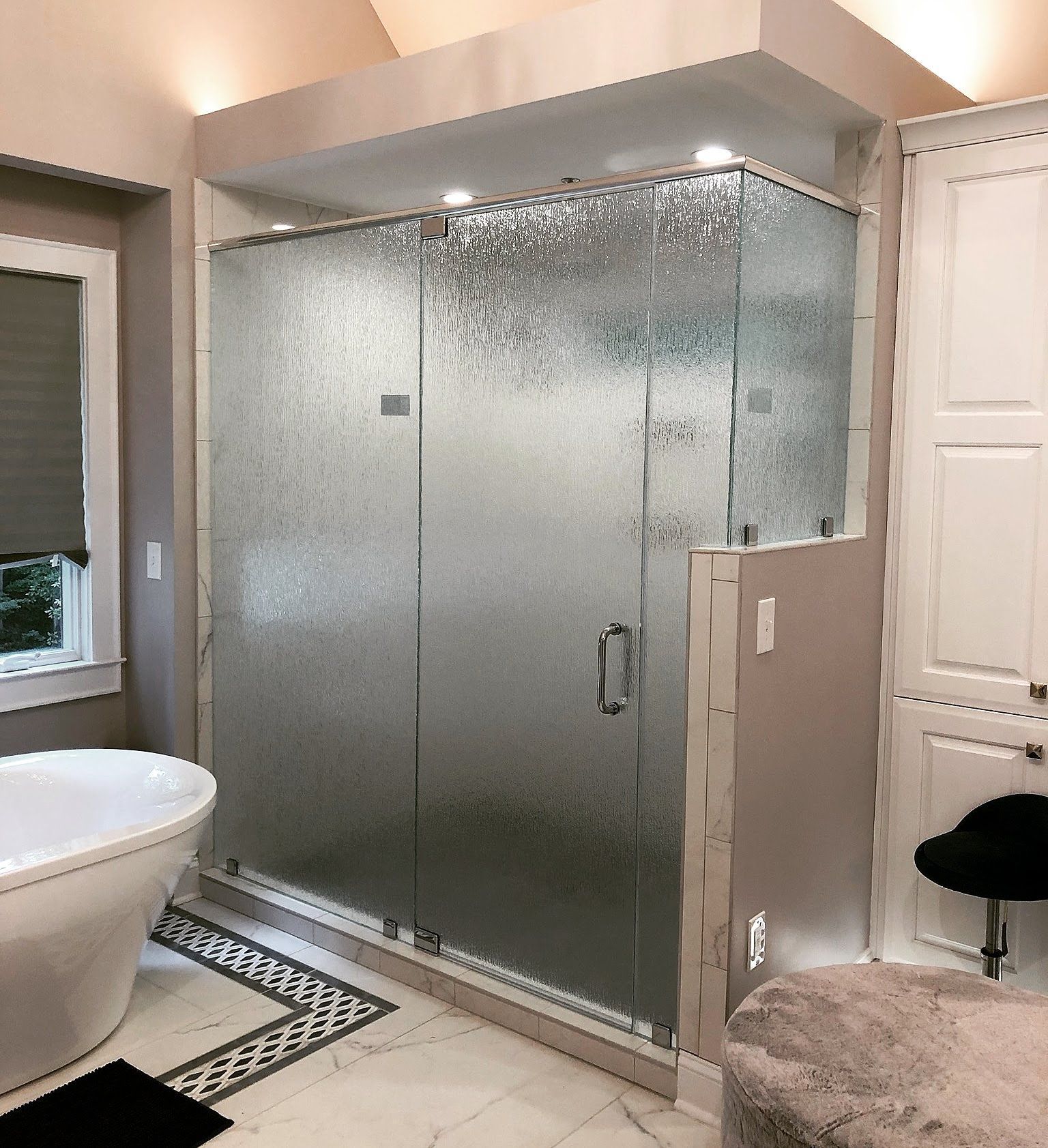 Bathroom with a large frosted-glass shower enclosure, white tub, and built-in cabinets.