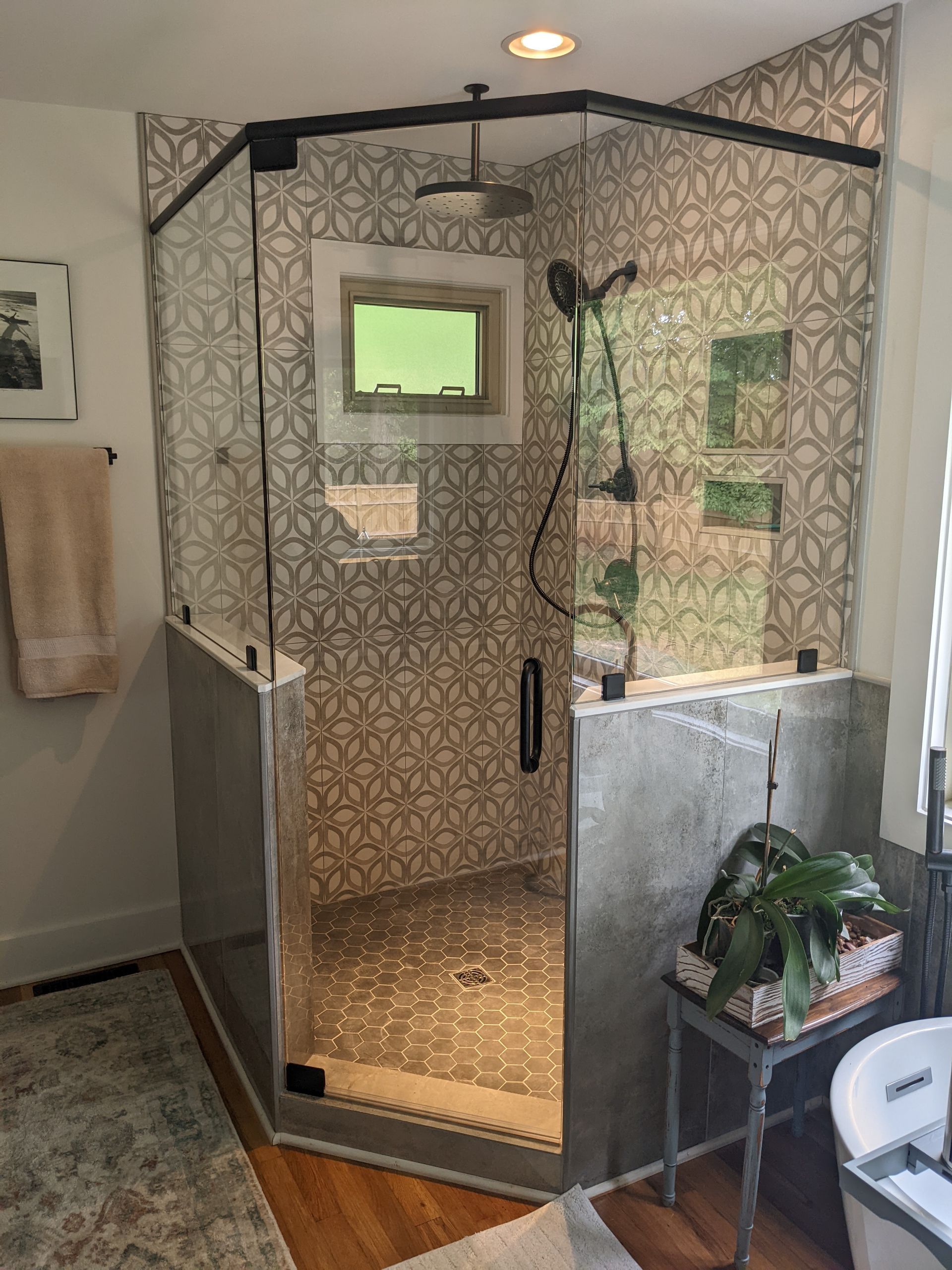 Modern tiled shower stall with glass door and ceiling light in a bathroom