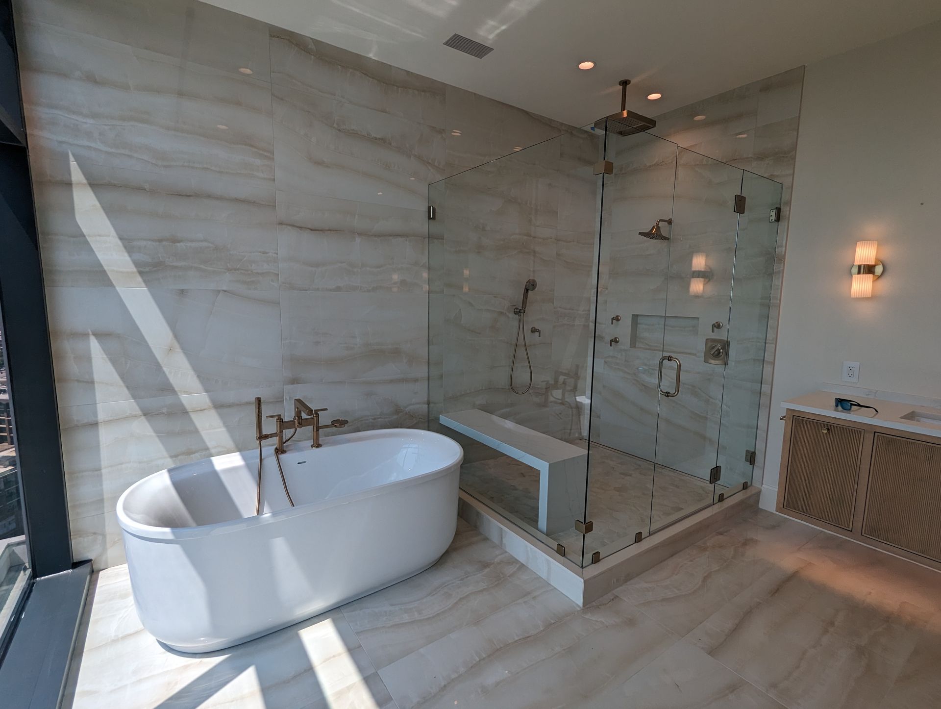 Luxury bathroom with freestanding tub, glass shower, and marble walls