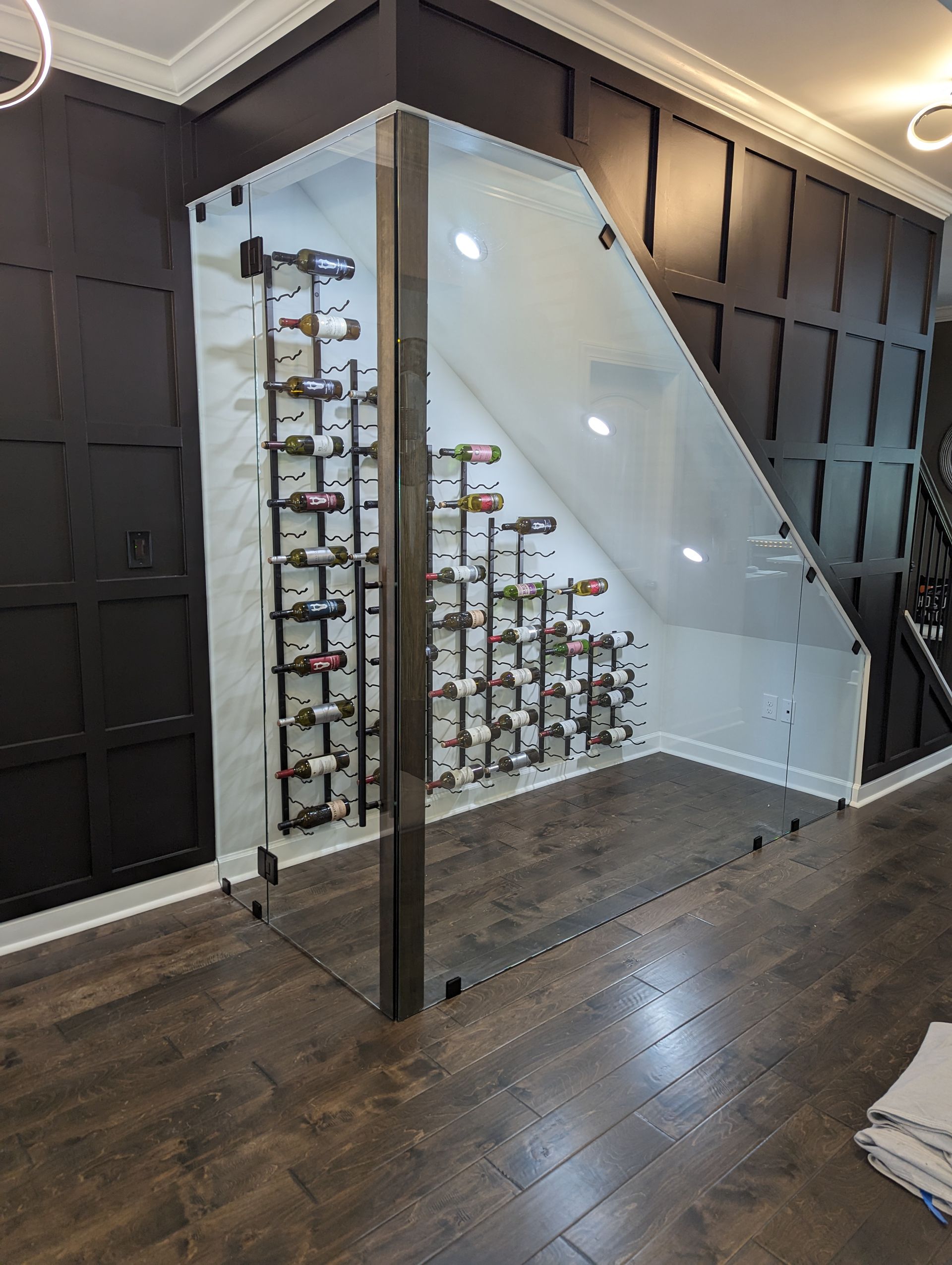 Glass stairway enclosure with a decorative metal railing in a dark wood hallway