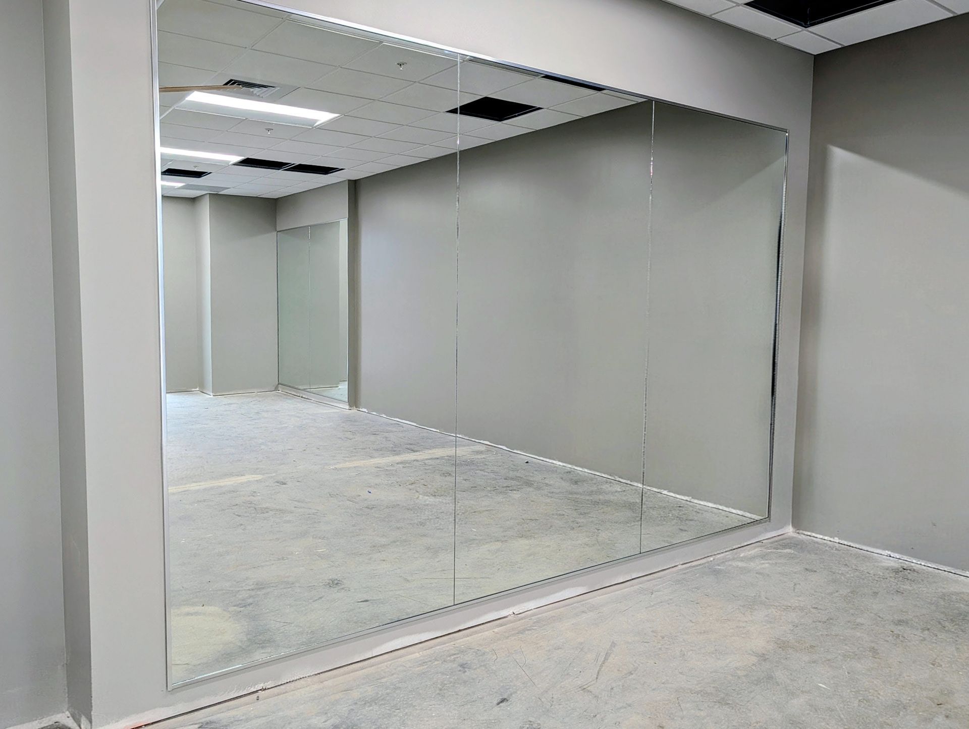 Empty office space with large mirrored wall and carpeted floor