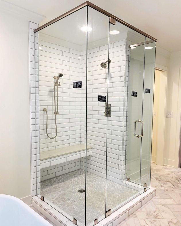 Glass walk-in shower with chrome fixtures, white subway tile walls, and marble-look floor.