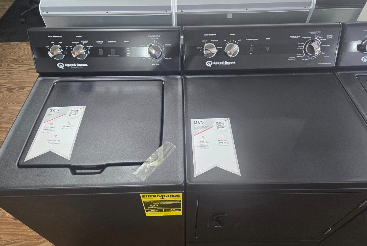 Black top-load washer and dryer set with control panels and price tags.